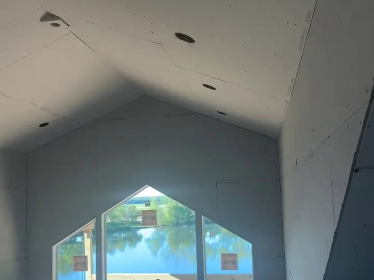 Vaulted living room with an arched window, drywall hung to the peak